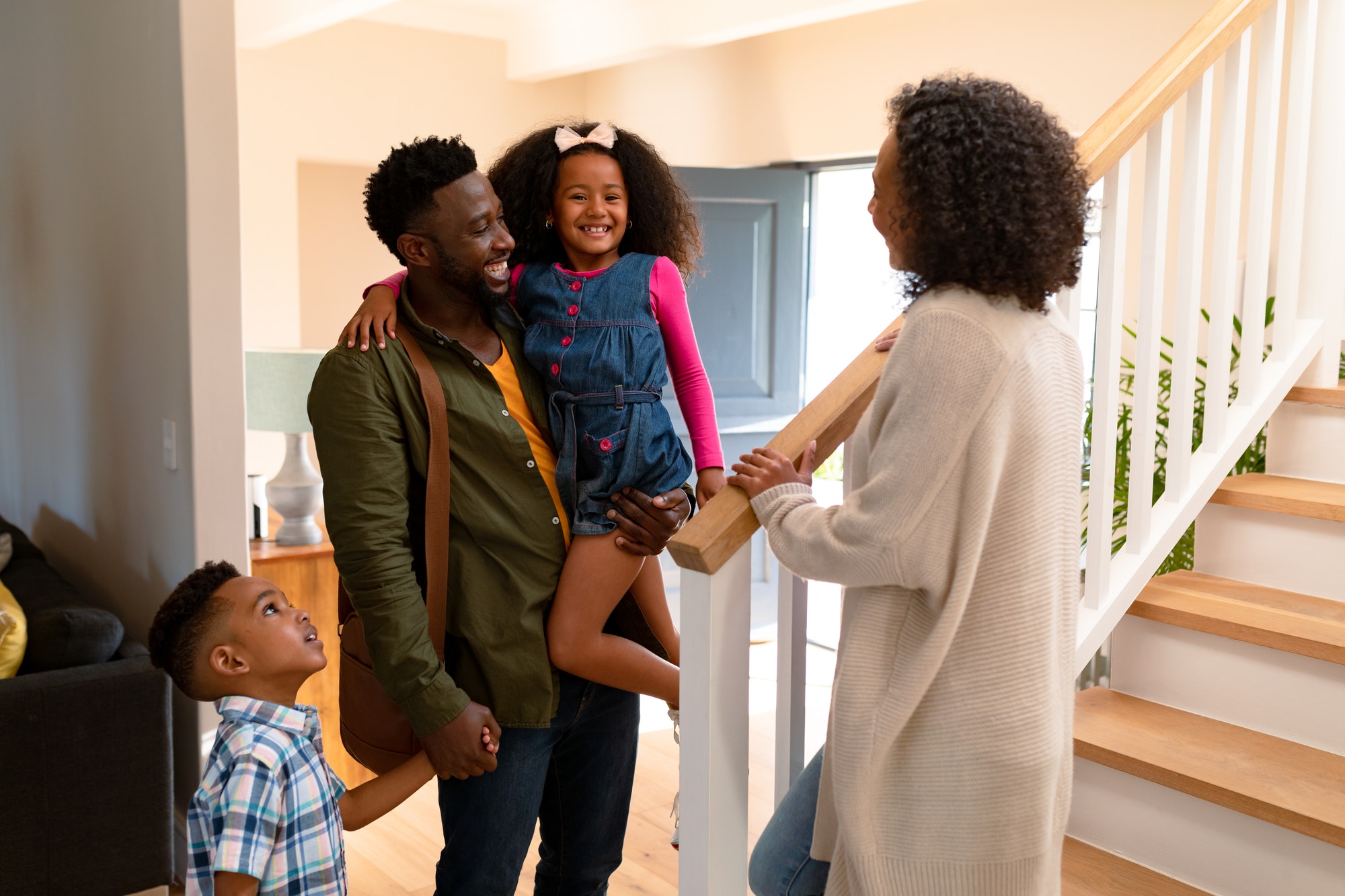 Happy african american family welcoming father coming back home