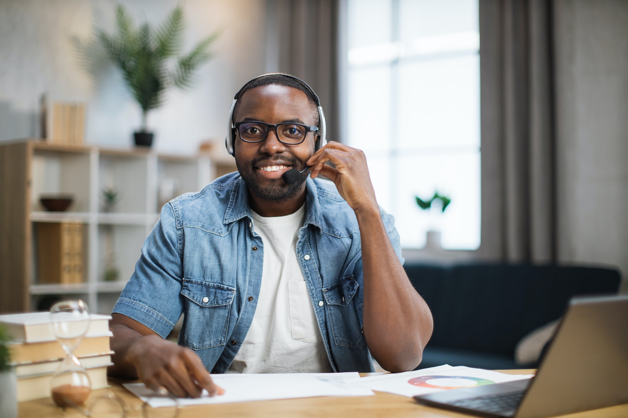 Man in headset smiling on camera while sitting at desk