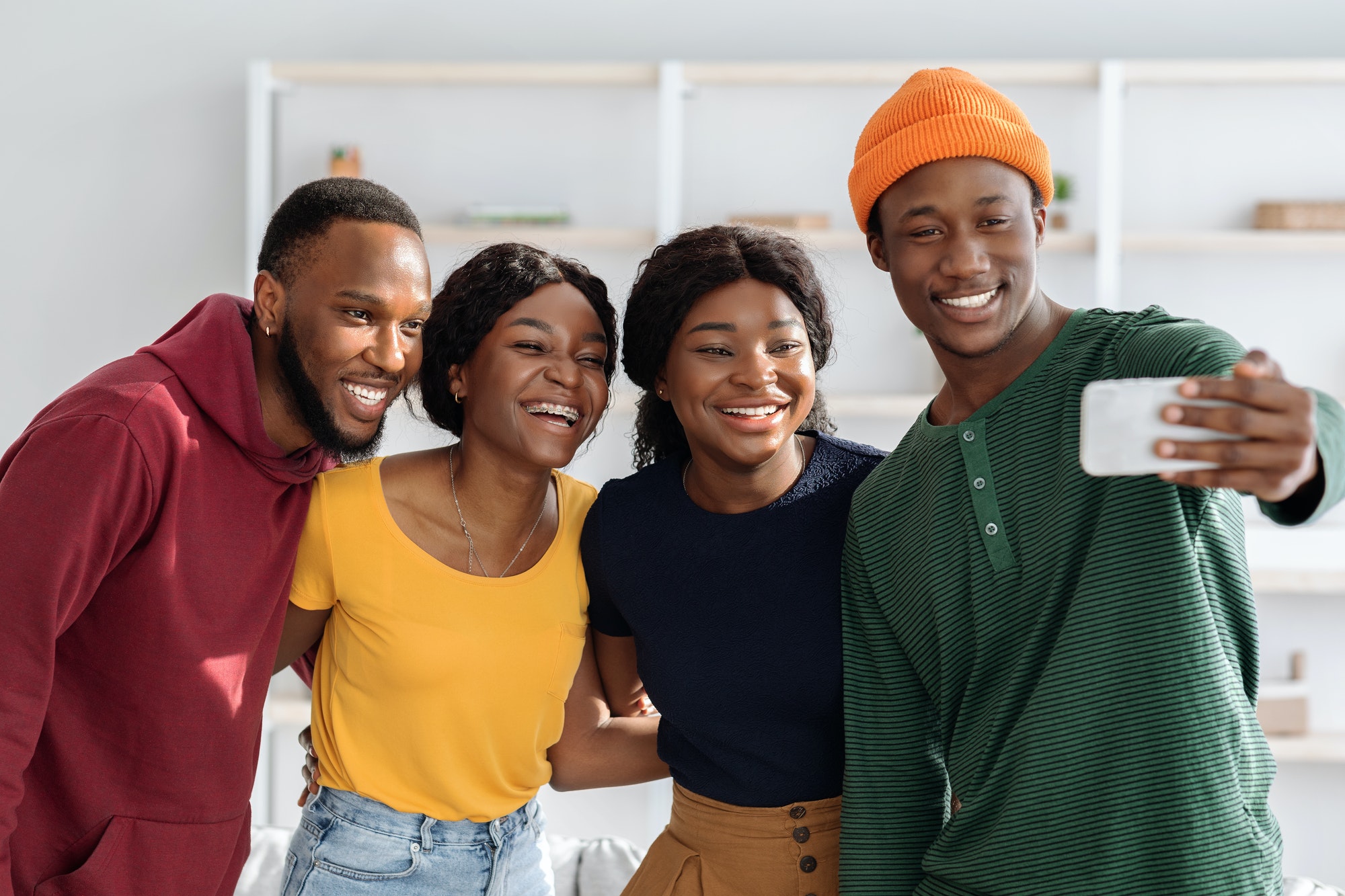 Positive black friends taking selfie while having party at home